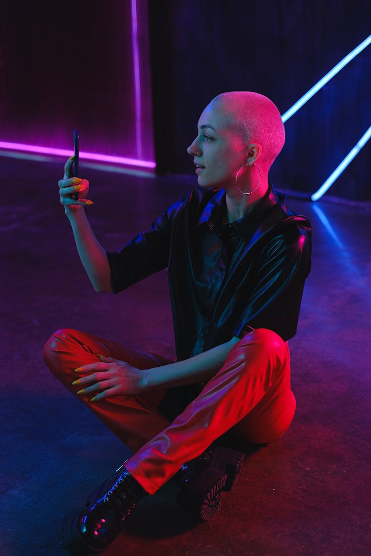 Positive Bald Woman Browsing Smartphone On Studio Floor