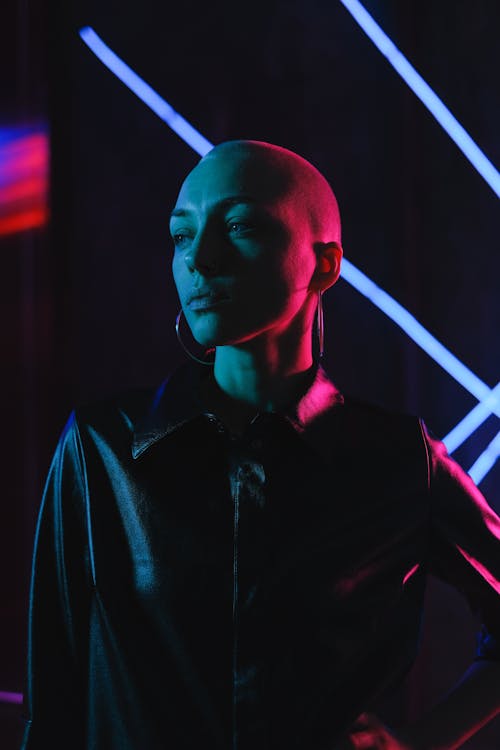 Free Pensive bald woman standing in neon lights in studio Stock Photo