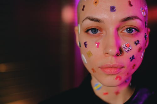 Crop unemotional woman with stickers on face in dark studio