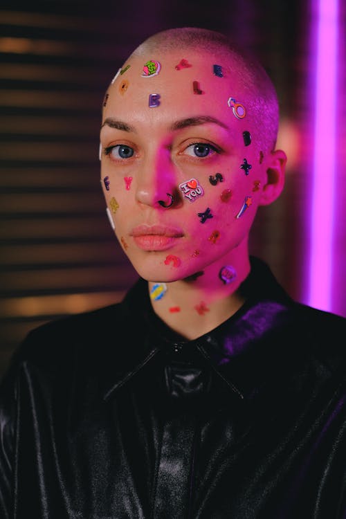 Unemotional bald woman with stickers on face in studio