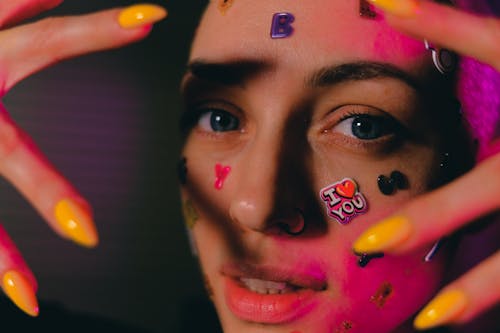 Crop bald woman with stickers on face in neon light