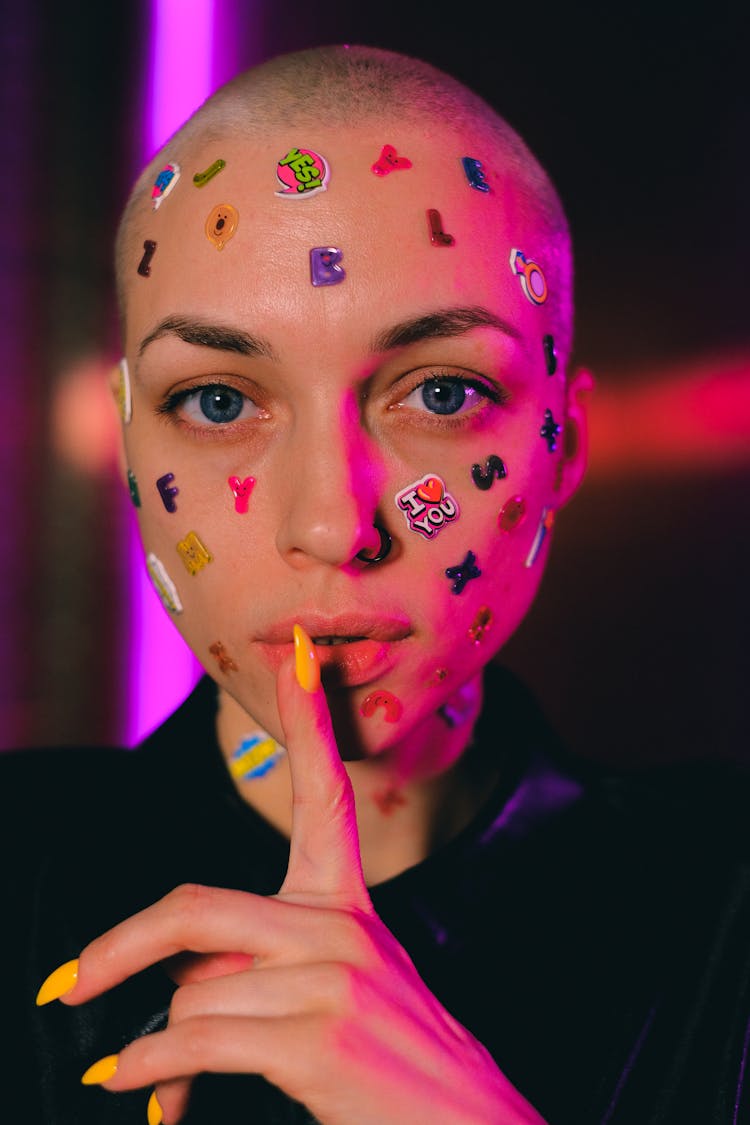 Bald Woman With Stickers On Face Showing Shush Sign