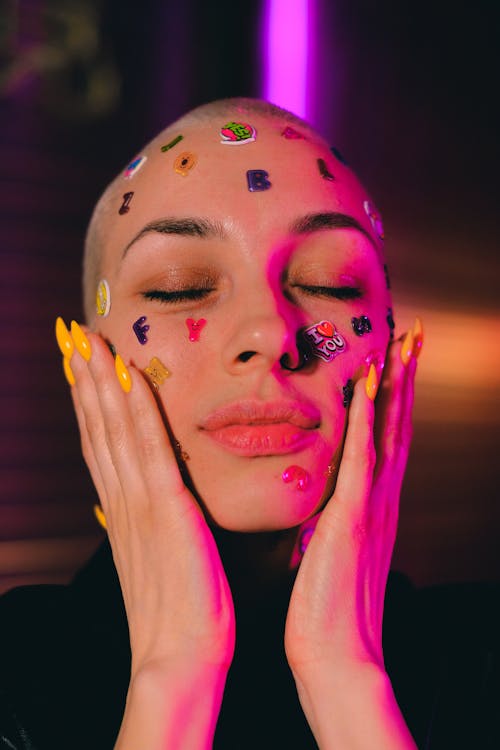 Free Bald woman with stickers on skin touching face in studio Stock Photo