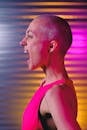 Side view eccentric bald female in pink top yelling loud in colorful studio