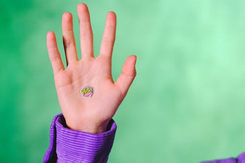 Free Crop anonymous person demonstrating sticker with word Yes placed on hand against green background Stock Photo