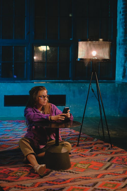 Unemotional woman using smartphone on hallway floor in evening