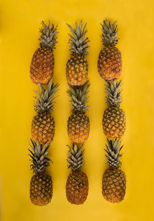 Arrangement of pineapples on yellow surface