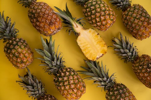Top view composition of fresh pineapples with juicy colorful flesh placed on yellow background in light studio during ripening season