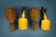 Top view of fresh whole and cut pineapples with green leaves and yellow flesh with pleasant aroma