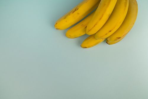 Free Top view of bundle of fresh bananas with spots on yellow peel on light background Stock Photo