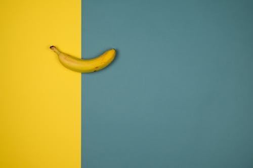 Overhead view of tasty fresh banana with spots on peel on two color background