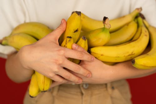 Faceless person with bunches of delicious fresh bananas