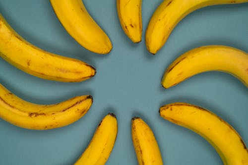 From above of delicious fresh bananas with blots on smooth peel on blue background