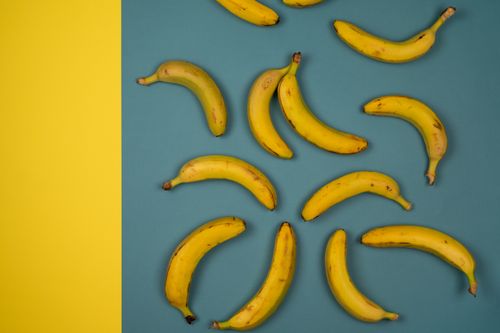 Free Top view of delicious ripe bananas with blots on smooth peel on blue and yellow background Stock Photo