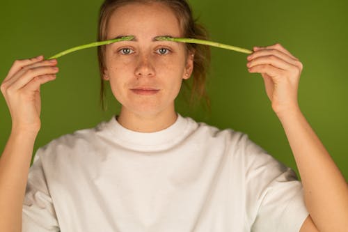 Crop woman with fresh asparagus stems on green background