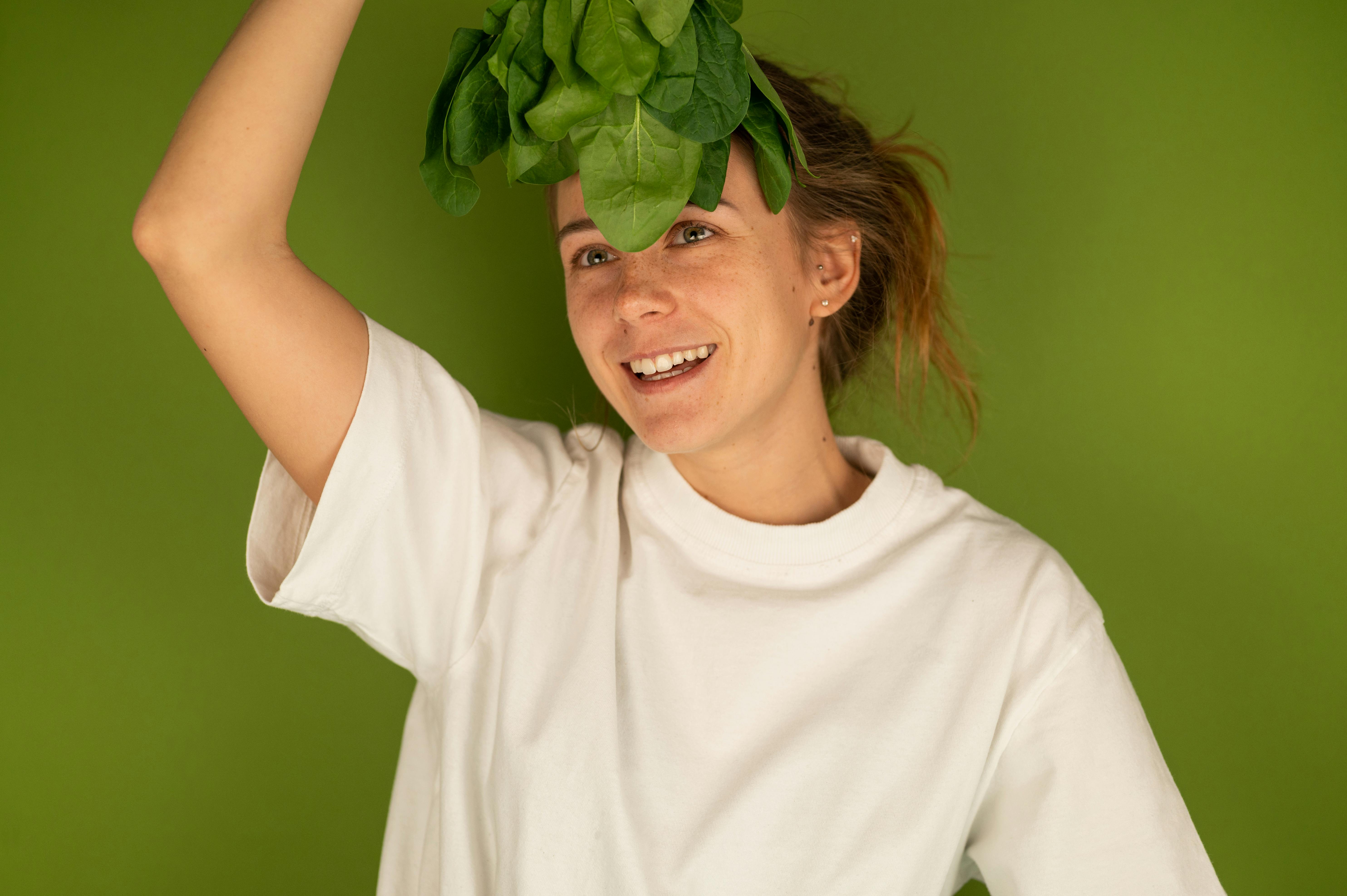 smiling woman with spinach leaves on green background