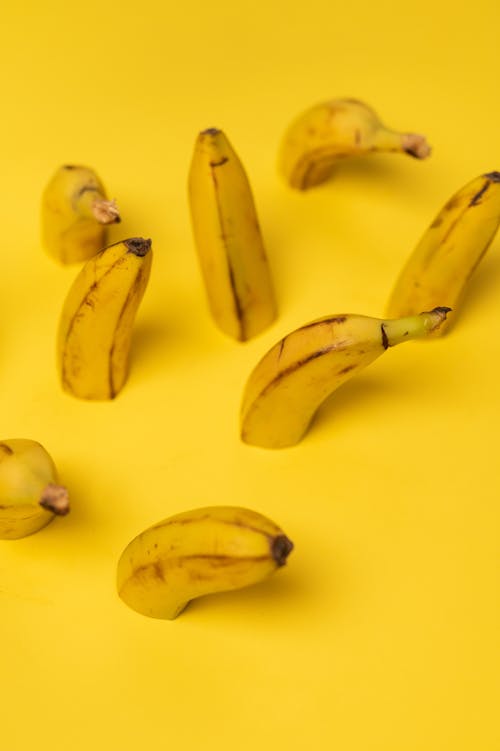 Fresh banana halves with stalks on yellow background