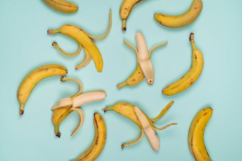 Top view of tasty ripe bananas with stems and blots on yellow peel on smooth surface