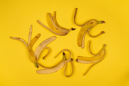 Fresh banana peel with stems on yellow background