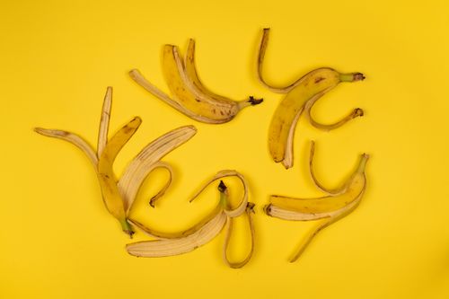 Free Top view of curved ripe banana peel with spots and stalks on bright yellow background Stock Photo