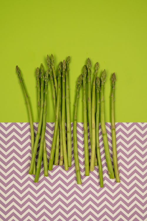 From above of uncooked asparagus stalks in row on smooth surface with wavy ornament