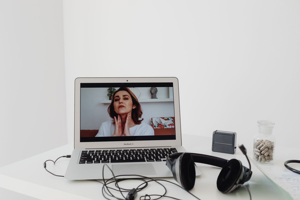 Frau bei einer Online-Physiotherapie-Sitzung per Videocall auf einem Laptop