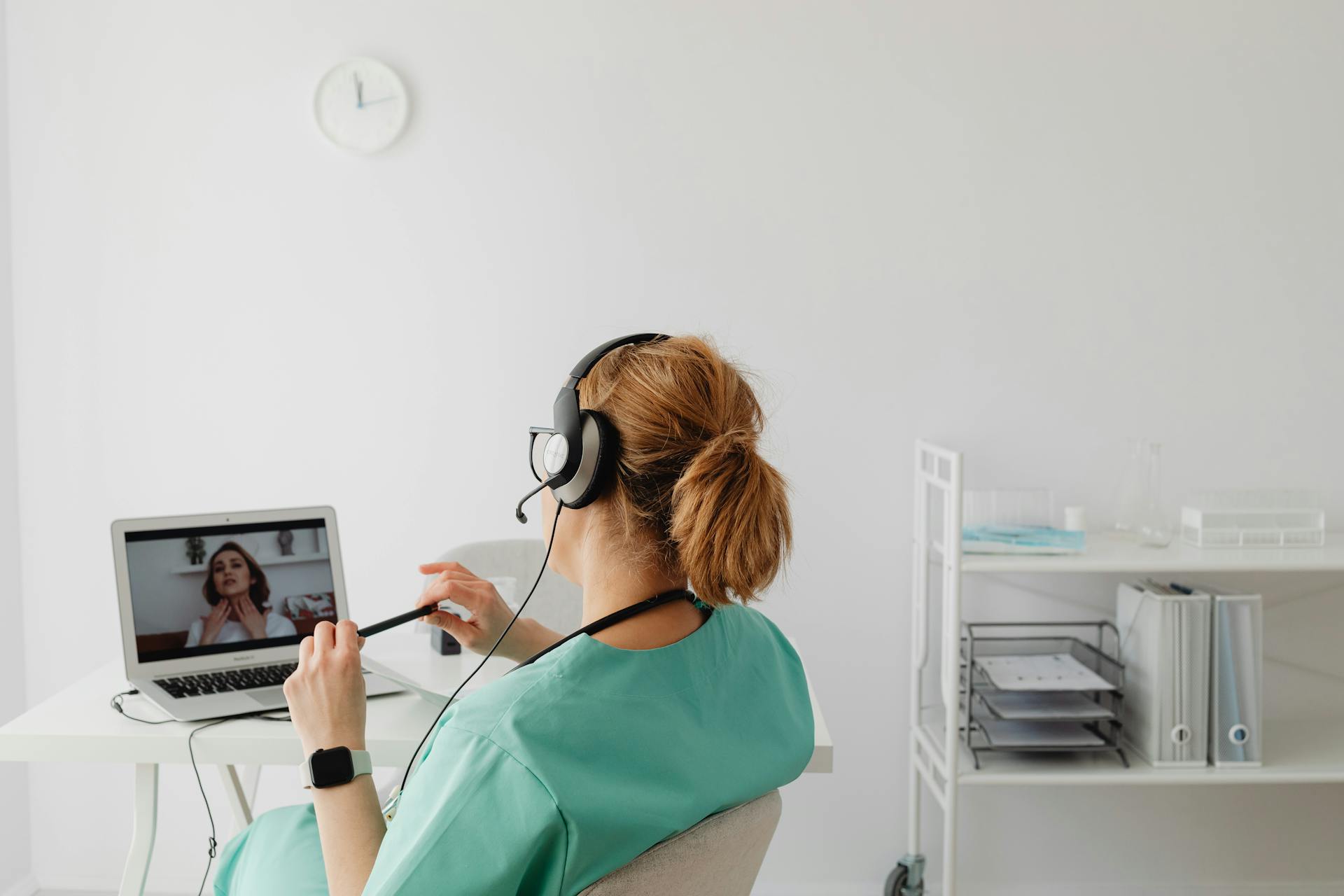 Medical professional conducting an online consultation via video call in a modern office environment.