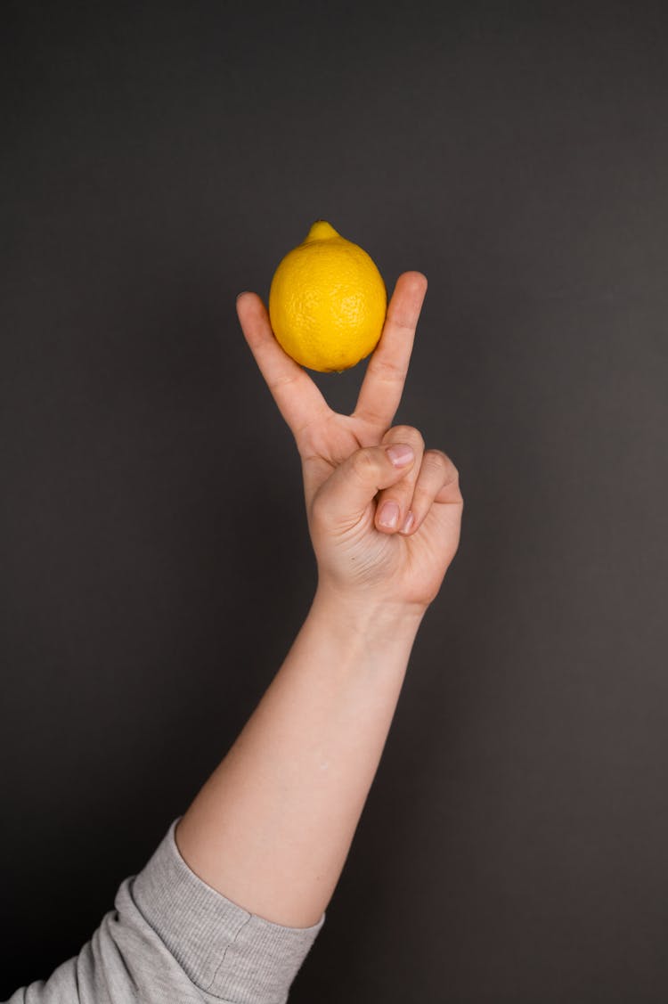 Crop Person With Lemon Showing Victory Gesture