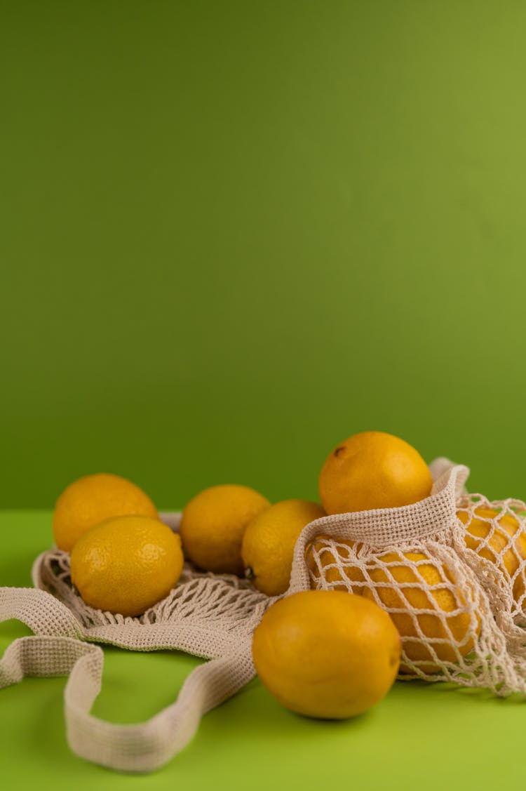 Fresh Lemons In Natural Bag On Green Background