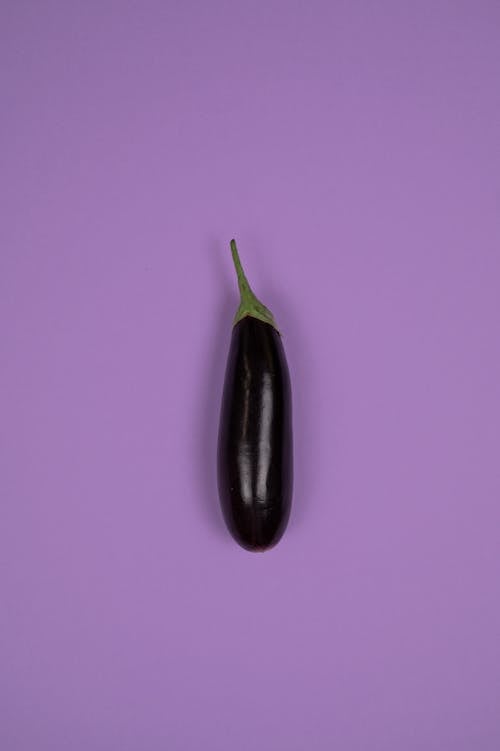 Fresh eggplant with stalk on purple background