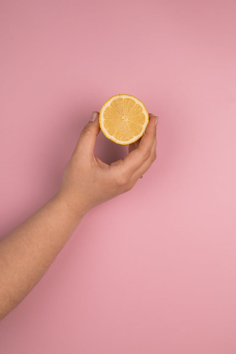 Crop Person Showing Cut Lemon On Pink Background