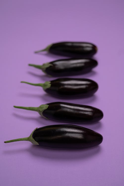 Fresh eggplants with stems on violet background