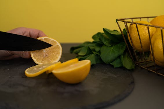 Faceless person cutting juicy fresh lemon on chopping board