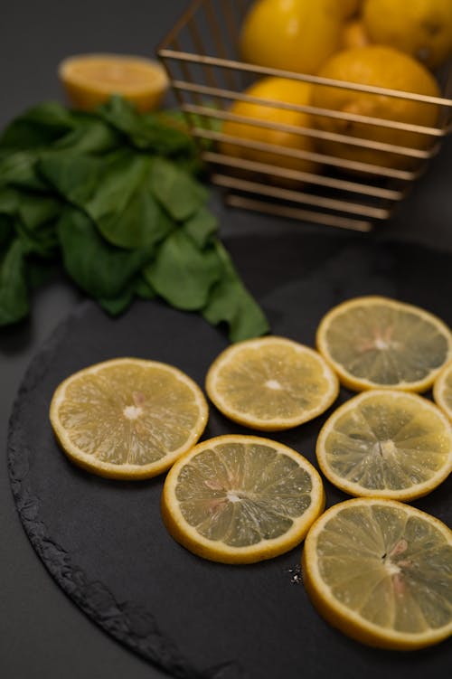 Free Fresh lemon slices on chopping board against spinach leaves Stock Photo