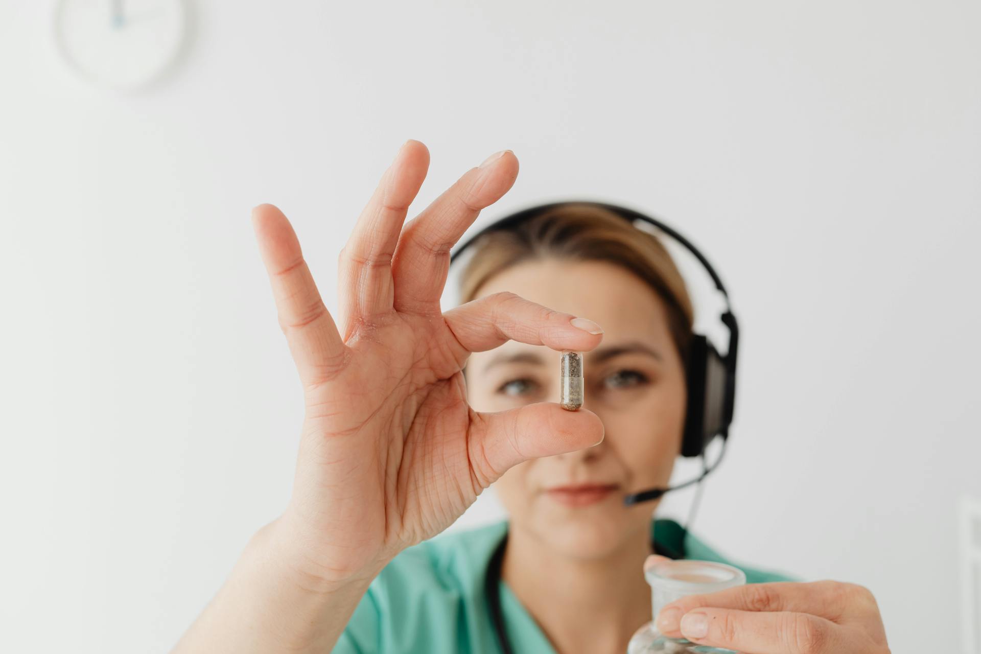 A woman in a headset holds a capsule, symbolizing healthcare support.