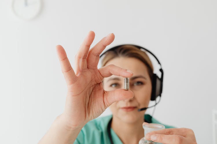 Woman Wearing Black Headset Holding A Capsule 