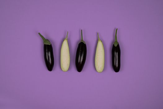 Top view of ripe isolated whole and cut eggplants placed on purple background