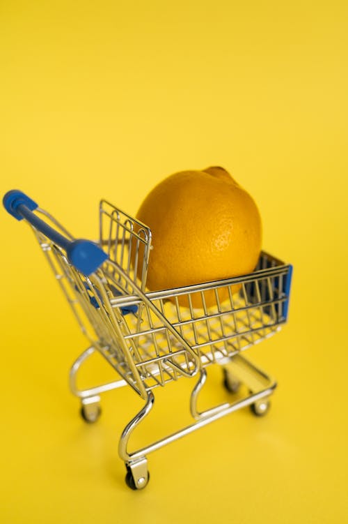 Isolated giant ripe lemon placed alone in shopping cart against yellow background