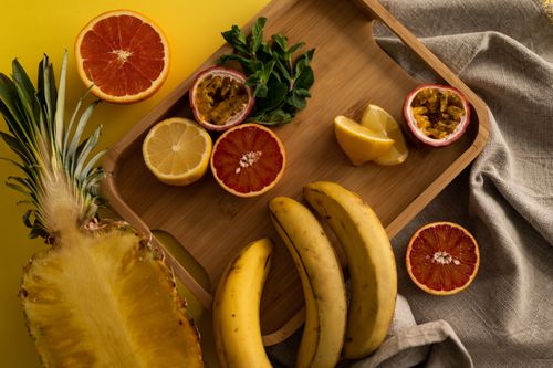 Free High angle of cut pineapple and banana with halves of grapefruit and passion fruit and sliced lemon on wooden tray Stock Photo