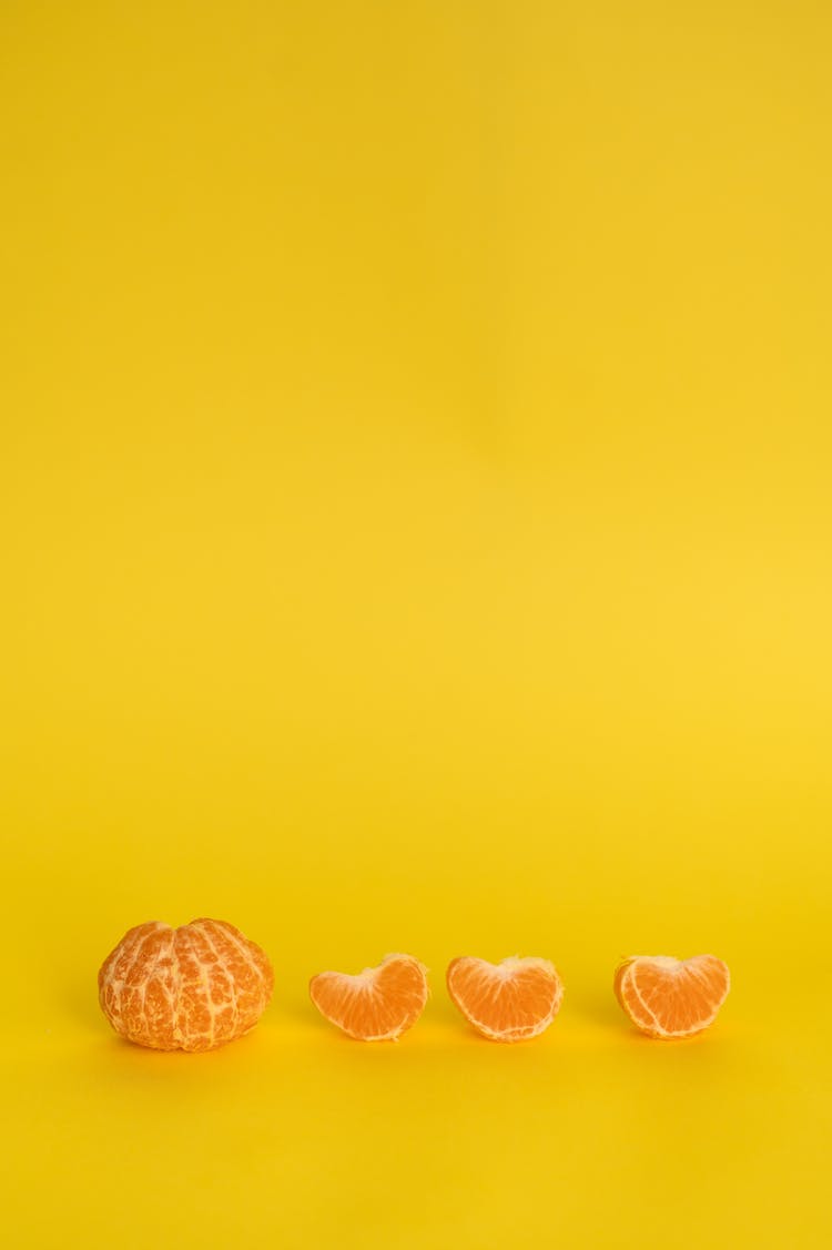 Peeled Mandarin With Slices Against Yellow Background