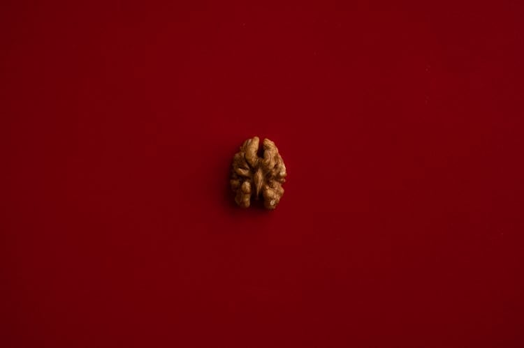 Half Of Walnut Kernel In Center Of Red Background