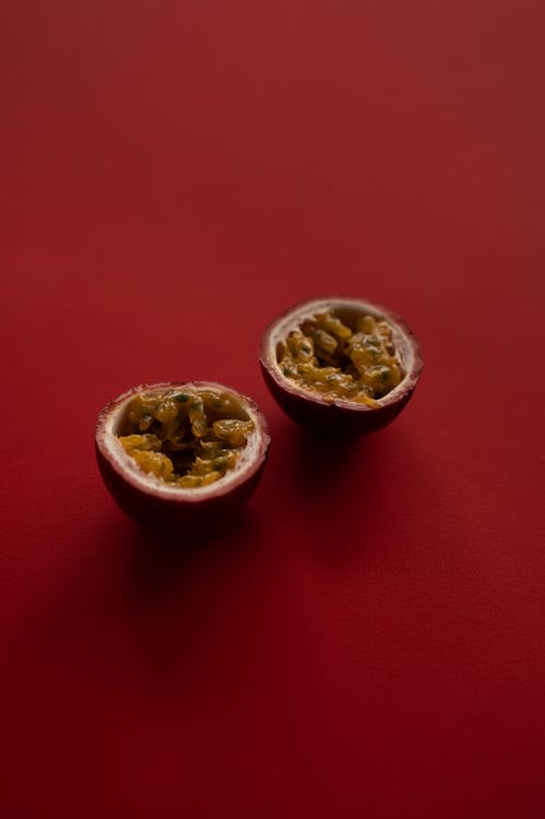 From above of delicious juicy passion fruit cut in half isolated on burgundy background