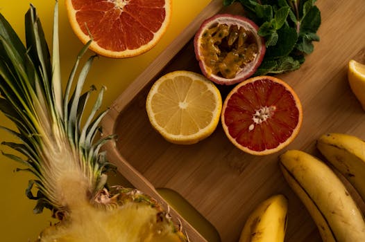 A vibrant assortment of fresh tropical fruits on a wooden board, captured from above.