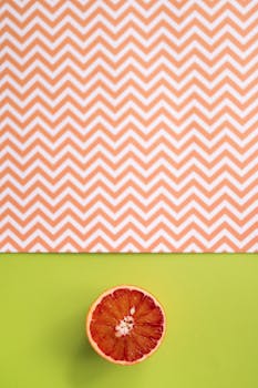 Sliced grapefruit on a vibrant green and zigzag patterned background, showcasing fresh and healthy food.