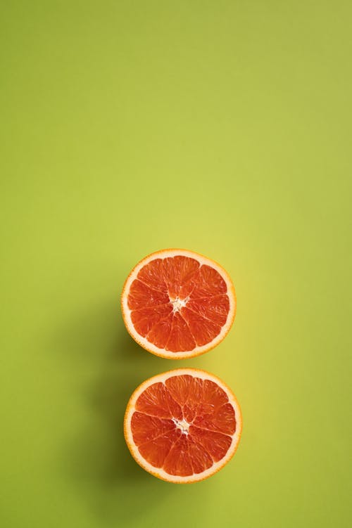 Sliced delicious citrus fruit on green background
