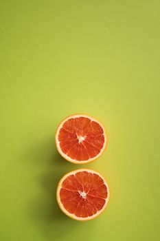 Top view composition of slices of yummy fresh grapefruit placed on bottom of green background