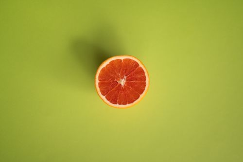 Free From above of slice of ripe juicy grapefruit isolated on centre of light green background Stock Photo