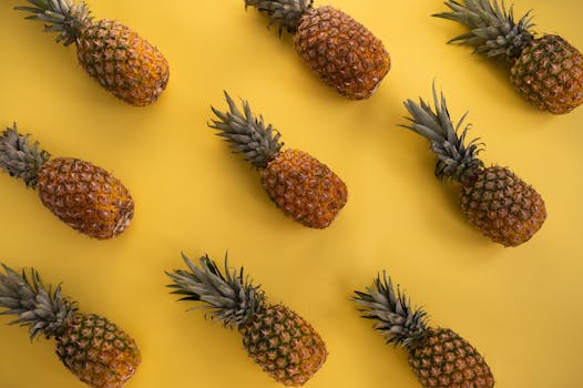 Top view of fresh pineapples on a vivid yellow background, perfect for tropical themes.