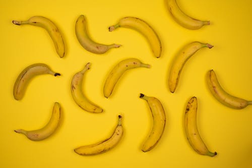 Top view of yummy ripe bananas placed at distance from each other on bright yellow background