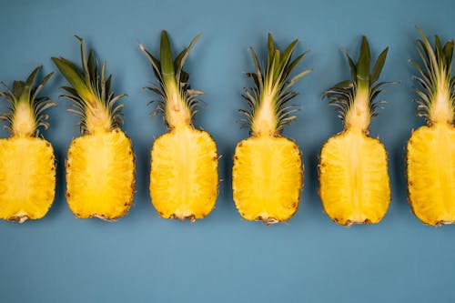 Halved pineapples on blue surface